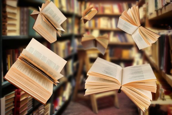 open books flying in a library setting