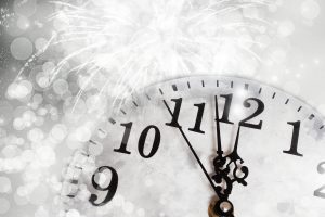 clock about to strike midnight surrounded by white sparkles